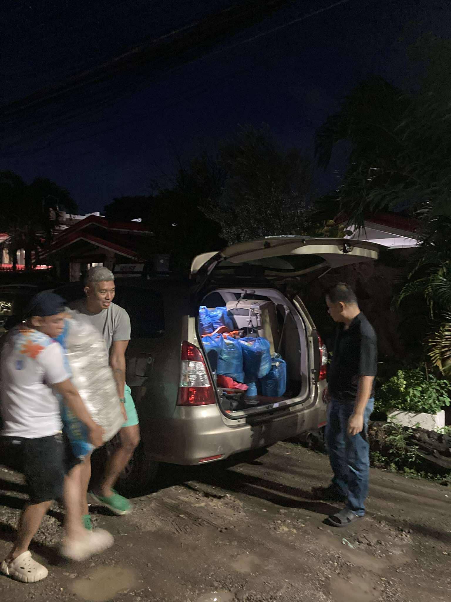 Volunteers loading bags of goods into a vehicle after dark